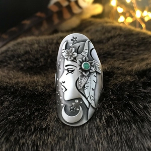 Primer plano de un anillo de plata vintage con retrato grabado y gema verde