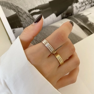 Close-up of stacked two-tone 925 silver rings with vertical texture worn on finger