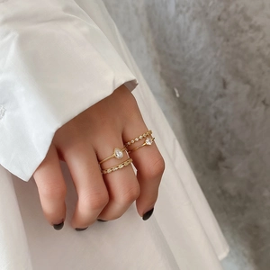 Golden ring set with white zircon stones worn by a model in a minimalist french style
