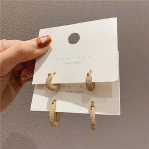 Macro detail of gold C-shaped earrings with micro-paved clear cubic zirconia on card