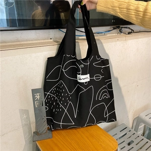 Detailed view of black canvas bag with white abstract lines and magnetic metal snap closure