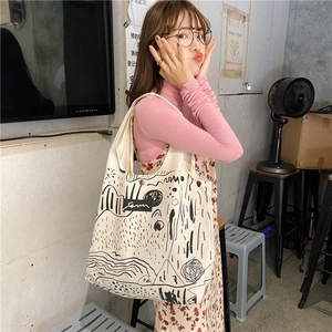 Detailed view of canvas tote bag featuring black abstract line art and doodle pattern