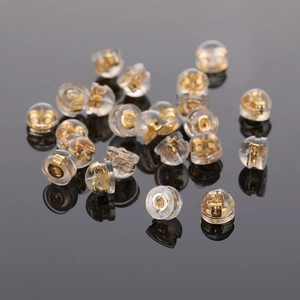 Détails macro des poussoirs d'oreilles en silicone et métal doré 18k sur fond réfléchissant