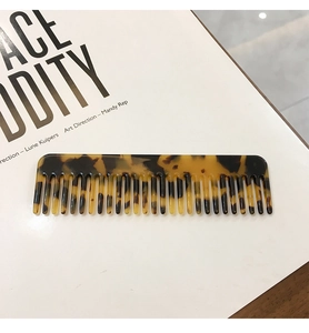 Close-up of leopard print hair comb with uniform teeth on a minimalist background