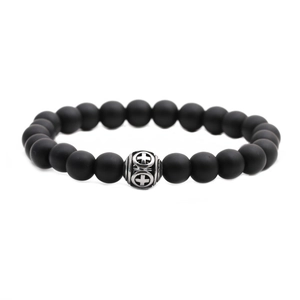 Matte black beaded bracelet with engraved silver stainless steel cross charm on white background
