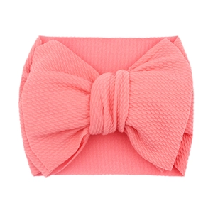 Soft pink textured fabric baby headband with a large decorative bow on white background