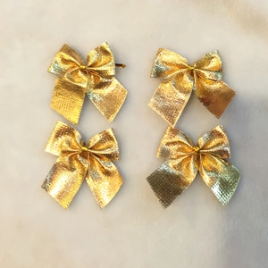 Détail de quatre nœuds de Noël à paillettes dorées sur une surface en marbre