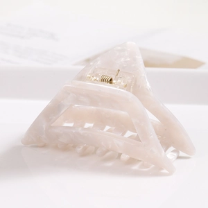 Detailed side view of a triangular acetate hair claw clip with cream marble texture