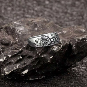 Vintage silver Evil Eye ring with gothic punk carvings on a dark textured rock surface