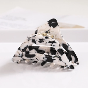 Detailed view of triangular acetate hair claw clip with black and white marble texture