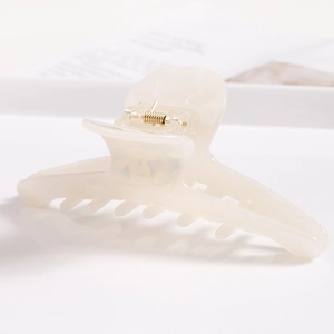 Macro side view of marble pattern cream hair claw clip with golden metal spring