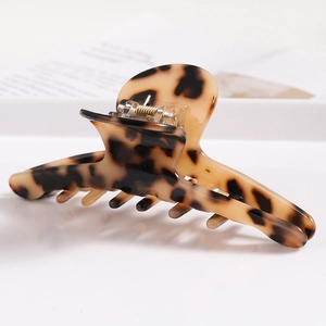 Detail of tortoiseshell acetate hair claw clip showing polished texture and metal spring