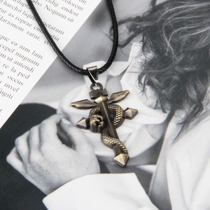 Detailed view of a vintage bronze cross pendant with a snake wrapping around spiked wings