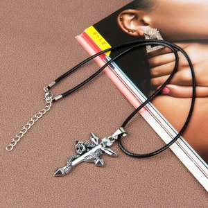 Detail of a vintage silver snake wrapped cross pendant on a black braided cord necklace