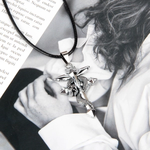Detail of silver Flamel cross pendant with snake and crown on magazine background