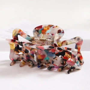 Detailed macro view of acetate hair claw clip with floral pattern and golden spring