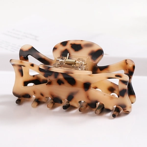 Detailed side view of a tortoiseshell acetate hair claw clip with a strong metal spring