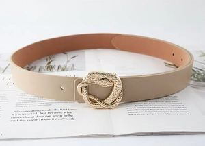Detail of a beige PU leather belt featuring a golden snake buckle on a magazine background