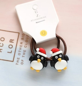 Close-up of brown elastic hair ties with cartoon penguin charms and Santa hats for kids
