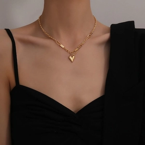 Gold heart pendant necklace with irregular chain on a model wearing black clothing