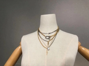 Detail of layered gold and silver chains with star, horseshoe and lightning pendants