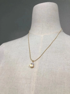 Detailed close-up of a pear-shaped rhinestone pendant on a gold bead chain necklace