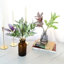 Lifelike artificial cotton plant with green leaves in a dark grey glass vase for home decor