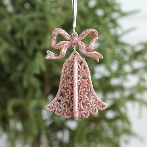 Pink gold Christmas bow bell ornament with glitter finish hanging on a green Xmas tree