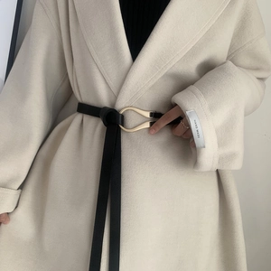 Detail of cream wool coat with black slim belt and gold U-shaped buckle detail