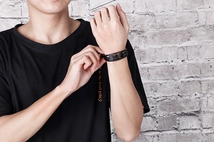 Detail of a black punk skull leather bracelet with hollow texture on a male model