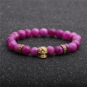 Dettaglio ravvicinato di perle di agata rosa da 8mm e teschio dorato su bracciale di perline