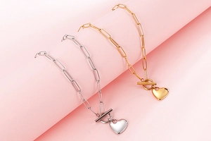 Close-up of gold and silver paperclip link necklaces with heart charms and toggle clasps