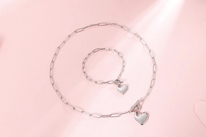 Close-up of silver paperclip chain necklace and bracelet set with heart pendants