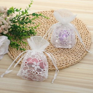 Close-up of floral organza drawstring pouches on a wooden table with small flowers
