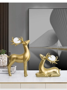 Detail von luxuriösen goldenen Elchstatuen mit Kristallkugeln auf weißem Marmortisch