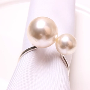 Elegant U-shaped silver napkin ring with two mismatched white pearls on white napkin