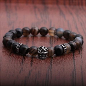 8mm dark bead bracelet with silver skull charm on rustic wood background