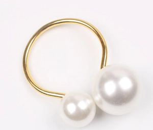 Detail of golden U-shaped napkin ring featuring two elegant white pearls on white background