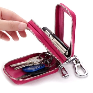 Dettaglio portachiavi in pelle rosa con cerniera, ganci interni e moschettone metallico