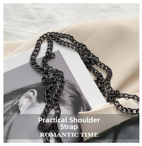 Close-up of dark nickel chain strap on black quilted crossbody bag with metal texture