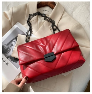 Detail shot of red quilted crossbody bag featuring V-shaped stitching and metallic clasp