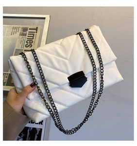 Detail of white quilted chain bag with V-stitch pattern and black geometric metal lock