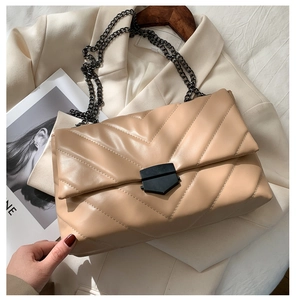 Close-up of beige quilted crossbody bag with V-shaped stitching and black metal rotary lock