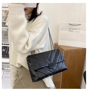 Detail of black V-quilted chain bag with glossy faux leather and stylish metal clasp