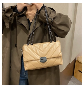 Close-up of beige quilted crossbody bag with V-shaped stitching and matte black chain