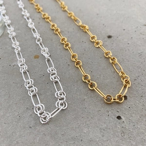 Detail of 925 silver and gold Figaro chains with interlocking circular link patterns