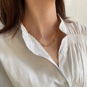 Close-up of minimalist golden 925 sterling silver circle necklace worn on a white shirt