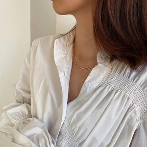 Detailed view of a minimalist golden chain necklace worn on a model's neck