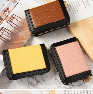 Close-up of crocodile pattern leather card holders in brown, yellow, and pink with gold zippers