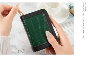 Close-up of a green crocodile embossed card holder with a gold zipper and ring pull